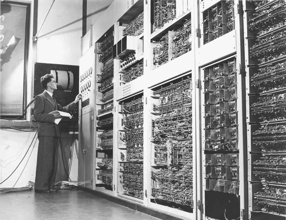 Old photo of man inspecting first generation computer