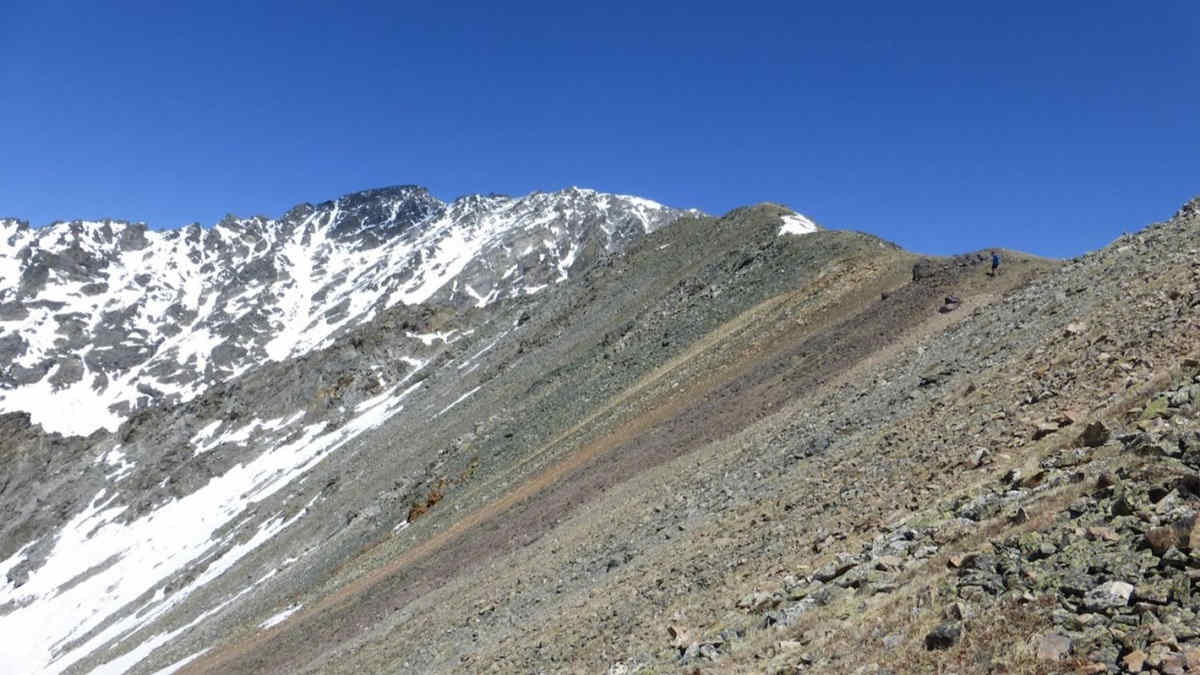 Snowy rocky mountain slope blue sky