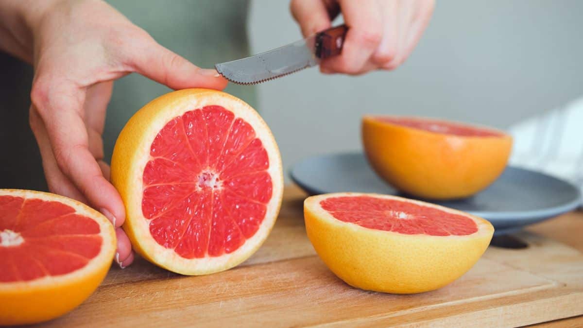 person chopping grapefruit on chopping board