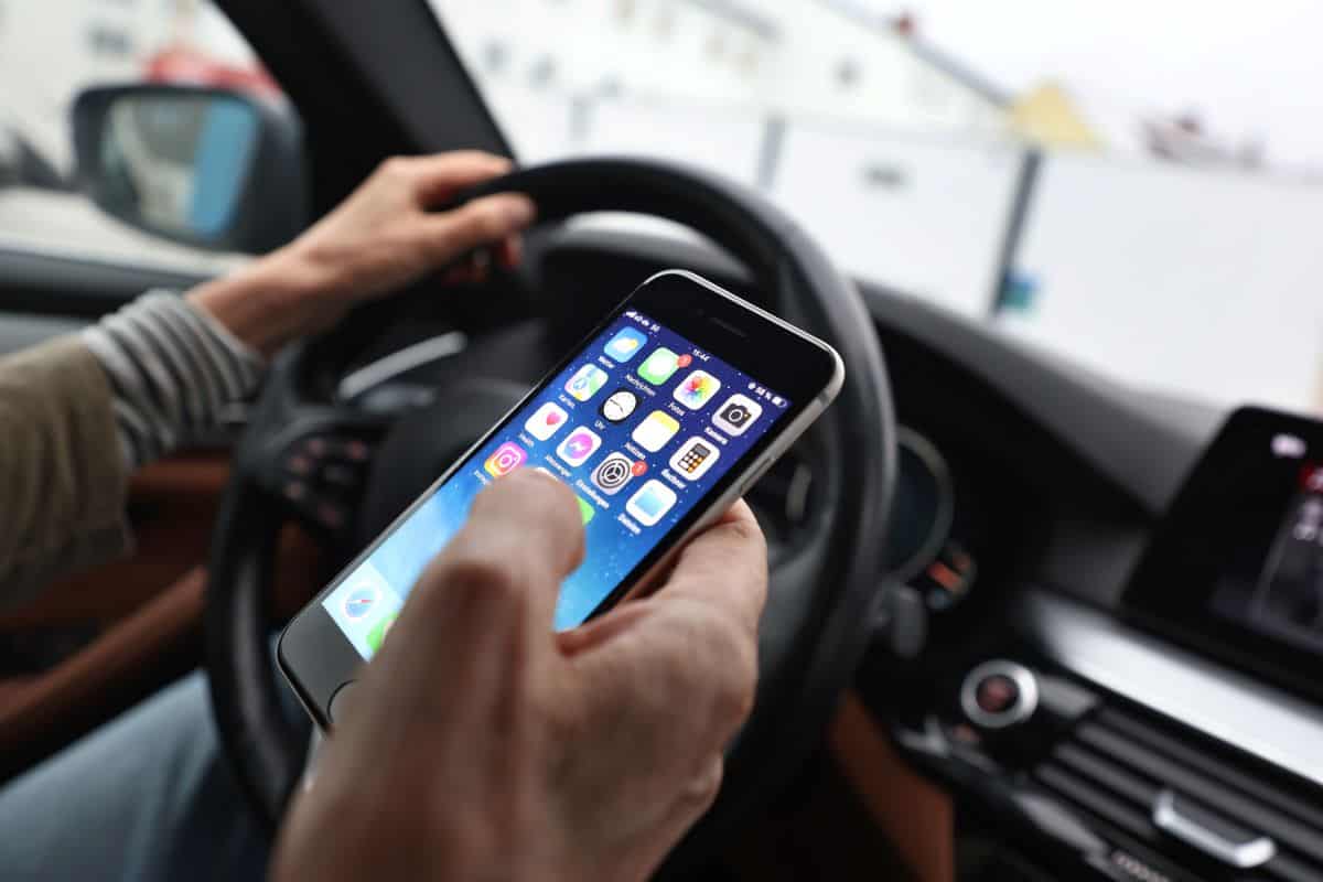 A woman sits behind the wheel of a car with a phone in her hand. Photo: Karl-Josef Hildenbrand/dpa (Photo by Karl-Josef Hildenbrand/picture alliance via Getty Images)