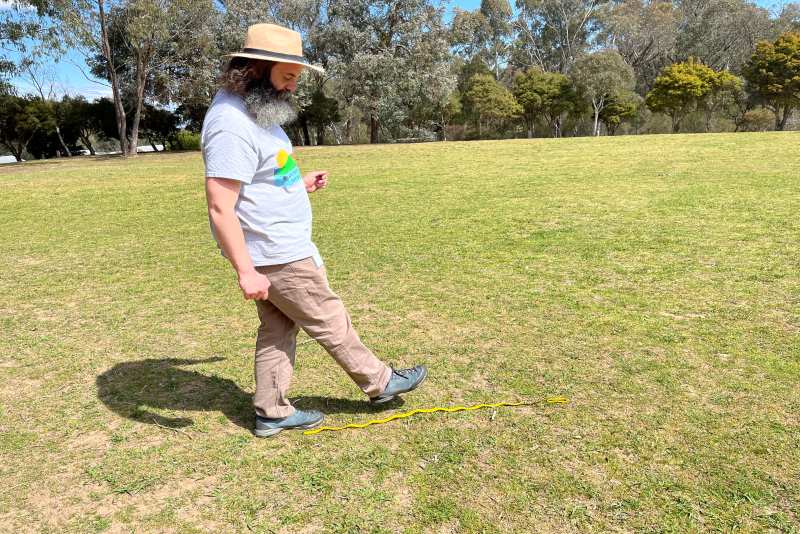 A man measures out a meter in a park as part of the make your own solar system activity