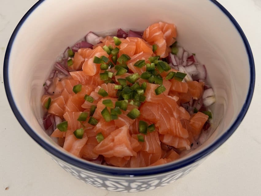 A bowl full of raw fish and vegetables, the beginnings of ceviche.