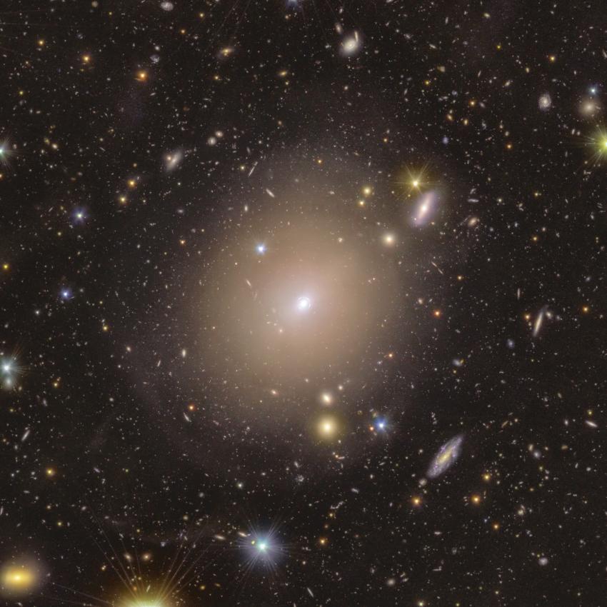 This wide field space photograph shows the extended stellar halo of ngc 6505 and showcases the einstein ring, surrounded by colourful foreground stars and background galaxies.