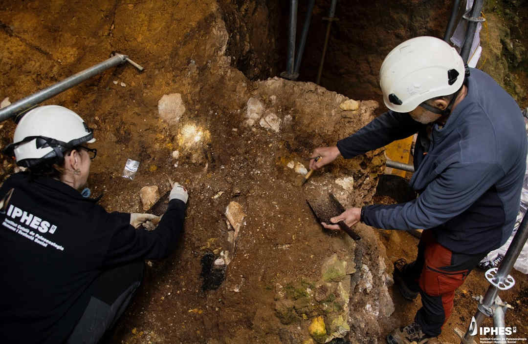 Two people in hard hats at archaeological dig site