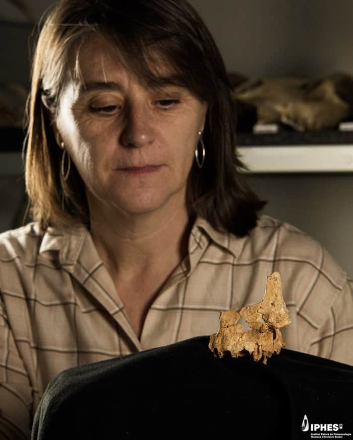 Woman looking at human face fossil bone fragment