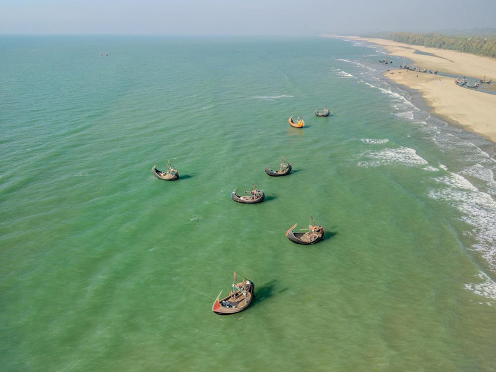 Traditional wooden fishing boats anchored in the turquoise waters near the sandy coast