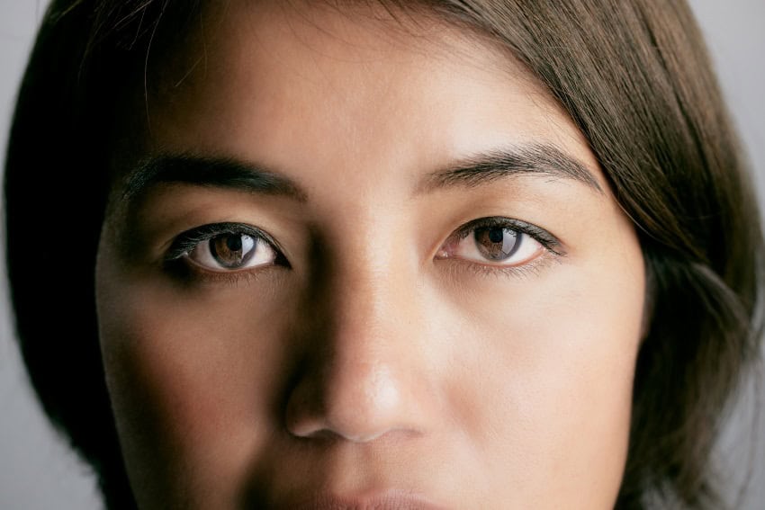 A woman with dark brown hair and brown eyes look at the camera