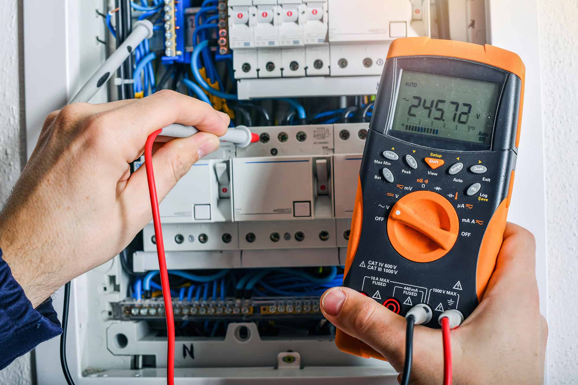 elektrieker of elektricien bezig met een zekeringen kast met meter