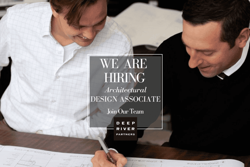 Two people reviewing architectural plan with text for hiring