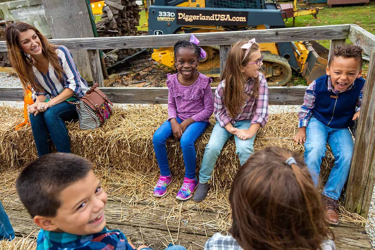 Children on hay ride laughing and smiling pulled through Diggerland USA