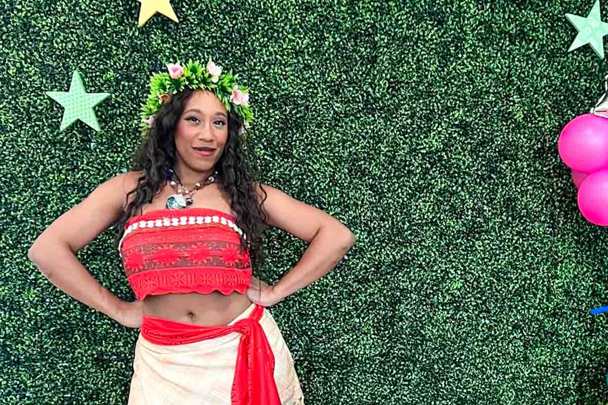 Princess wearing flower crown smiles and stands for a photo at a birthday party with her hands on her hips.