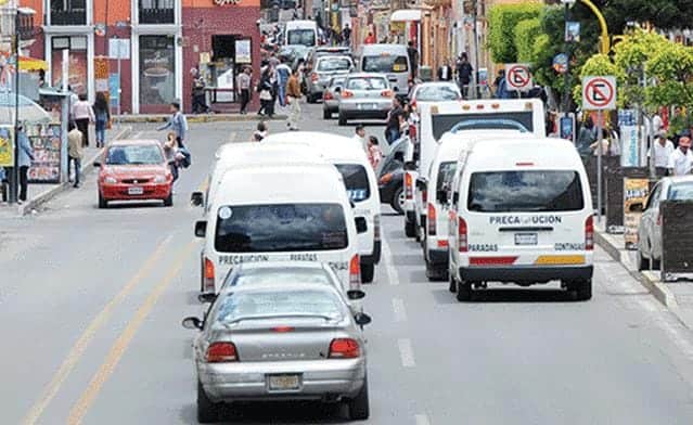 Autos y transporte en la calle en Tlaxcala, México, con peatones y señalización vial visible en un entorno urbano concurrido.