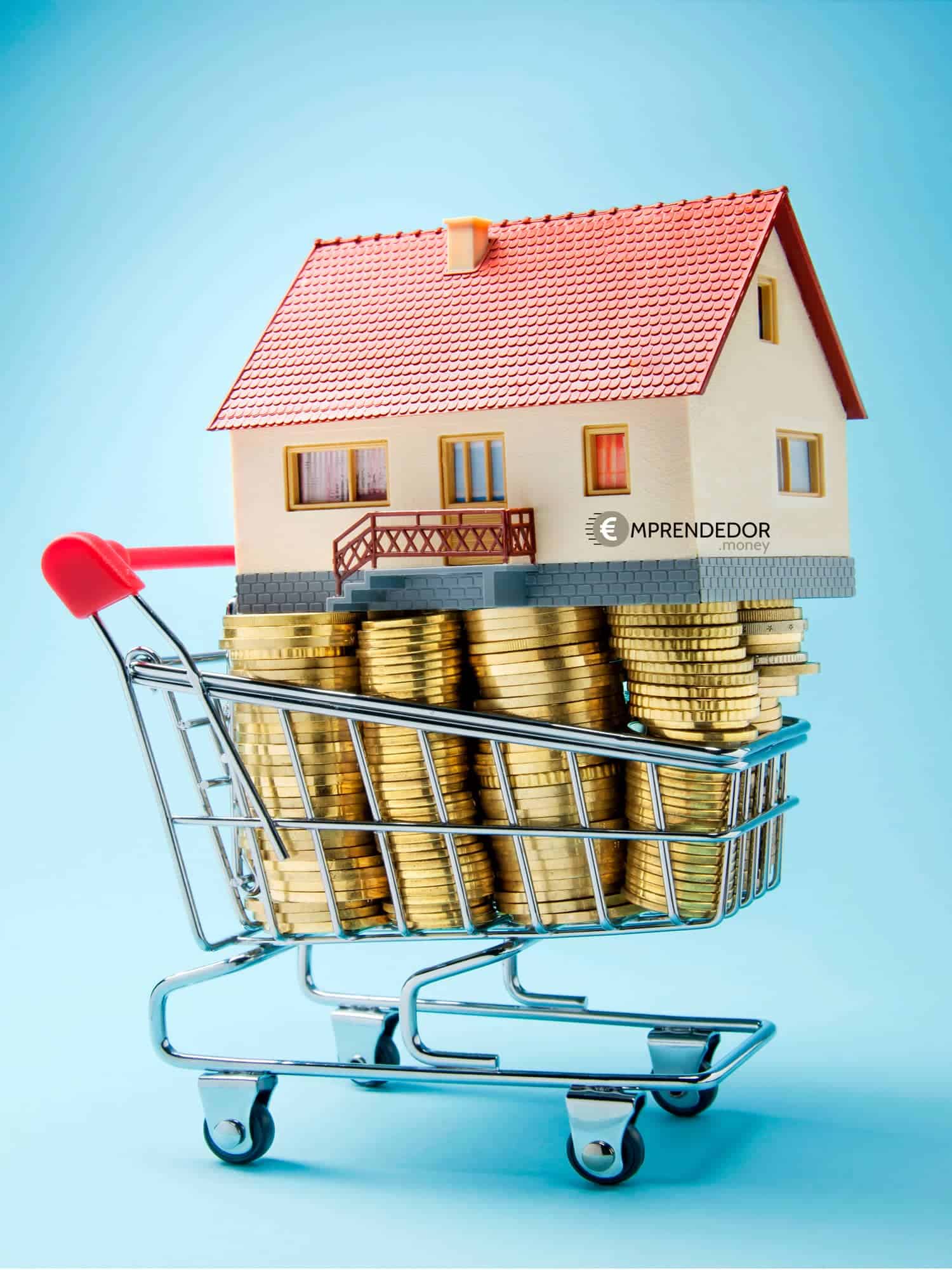 Casa miniatura sobre un carrito de compras lleno de monedas.