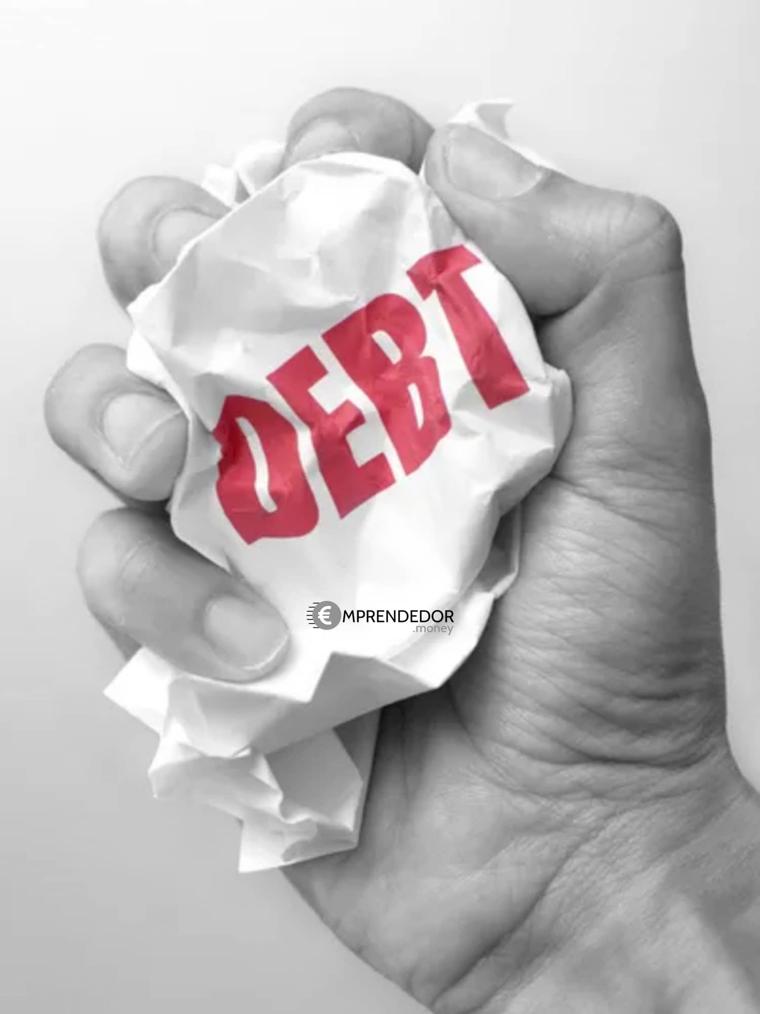 Mano arrugando un papel que dice DEUDA, representando cómo pagar deudas con el método avalancha o bola de nieve.