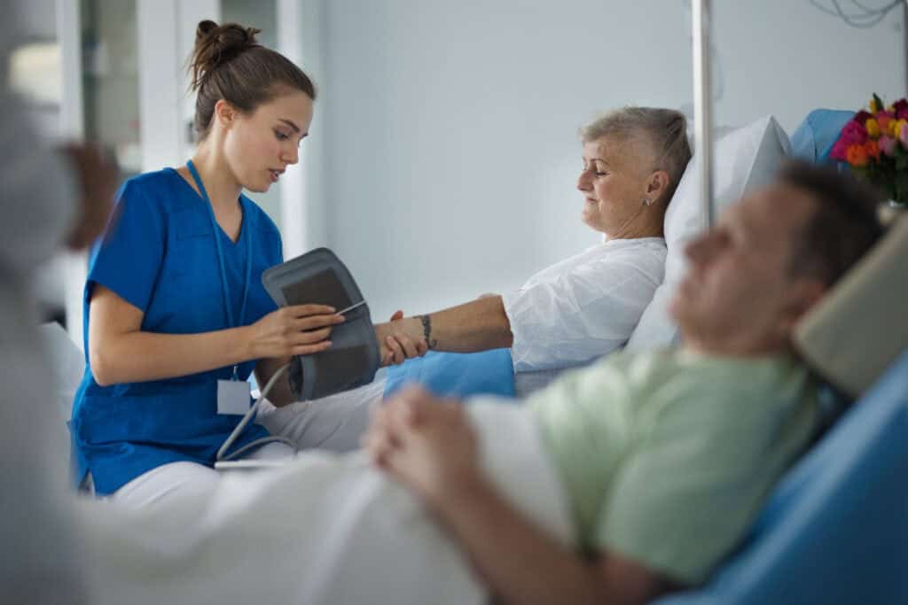 Young nurse chcecking blood presure to senior patient.