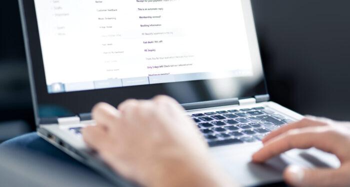 Email inbox full of messages and text. Man reading electronic mail with laptop. Spam, junk and e marketing on screen. Looking and checking received posts. Busy entrepreneur working and using computer.