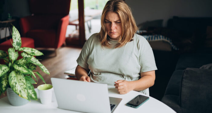 Frustrated young adult woman looking in laptop computer in home. Negative people emotion