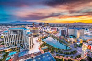 A welcoming aerial view of the Las Vegas Strip at sunset, highlighting iconic hotels, vibrant casinos, and a stunning fountain that reflects the importance of reliable plumbing. The replica Eiffel Tower stands tall against a backdrop of beautiful mountains. This scene captures the energy and comfort that Fetch‑A‑Tech proudly brings to homes and families across Las Vegas with our honest, family-owned service.
