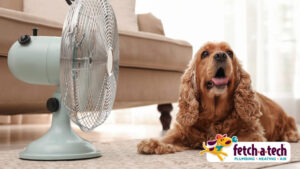 A happy brown dog relaxes on a cozy rug in a Las Vegas living room, enjoying the cool breeze from an electric fan. The Fetch‑A‑Tech logo appears in the corner, representing our honest, family-owned team dedicated to keeping your home comfortable and your loved ones cared for.