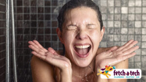 A woman enjoys a relaxing shower with a contented smile, her hands raised as warm water gently falls over her face. The Fetch‑A‑Tech Plumbing, Heating & Air logo appears in the corner, highlighting our commitment to providing friendly, reliable comfort for families in Las Vegas.