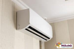A white wall-mounted air conditioning unit is installed high on the wall, providing cool comfort for your Las Vegas home. The Fetch‑A‑Tech logo appears in the bottom right corner, reflecting our family-owned commitment to helpful, reliable service you can trust.