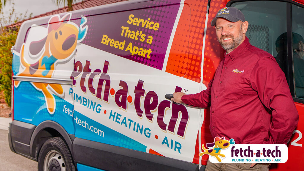 A friendly Fetch‑A‑Tech technician, dressed in a maroon shirt and cap, stands next to a brightly wrapped service van featuring plumbing, heating, and air services. The scene highlights Fetch‑A‑Tech’s helpful team and commitment to comfort for Las Vegas families.