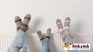 Three people wearing fun, patterned socks relax with their feet up on a cozy white radiator—showing just how comfortable your Las Vegas home can feel with help from Fetch‑A‑Tech. Our family-owned team is here to keep you warm and worry-free. The Fetch‑A‑Tech logo appears in the bottom right corner.