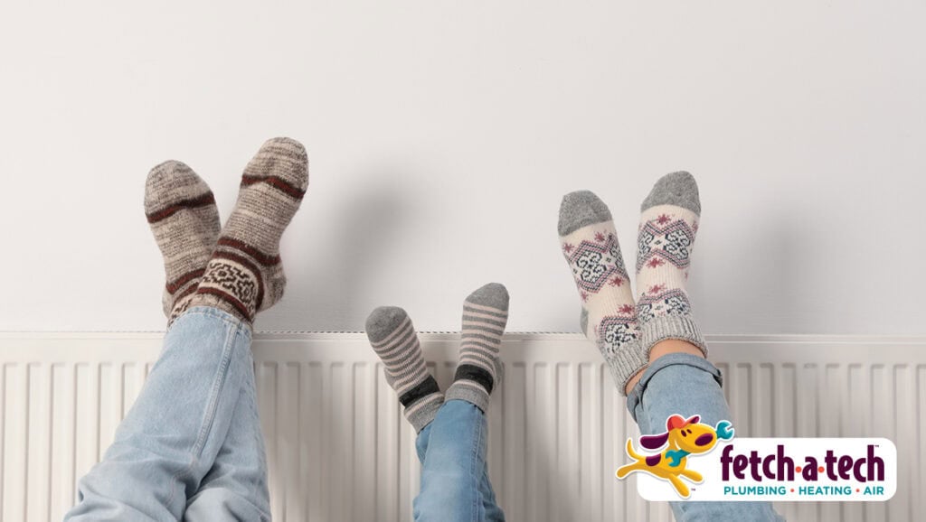 Three people wearing fun, patterned socks relax with their feet up on a cozy white radiator—showing just how comfortable your Las Vegas home can feel with help from Fetch‑A‑Tech. Our family-owned team is here to keep you warm and worry-free. The Fetch‑A‑Tech logo appears in the bottom right corner.