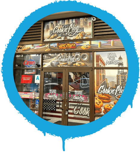 Fun and colorful storefront with a graffiti sign that says 'Cookie Plug' with large images of chocolate chip cookies in the window