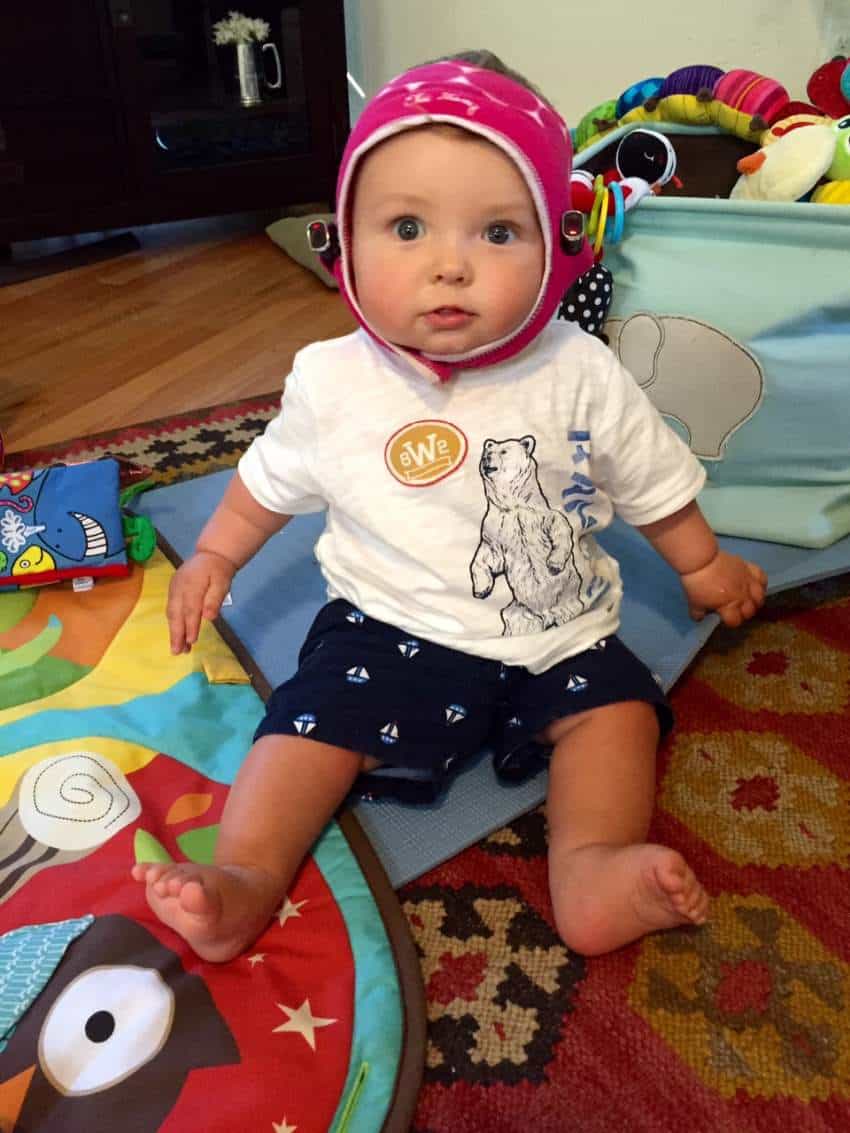 Baby wearing pink cap with small cameras attached