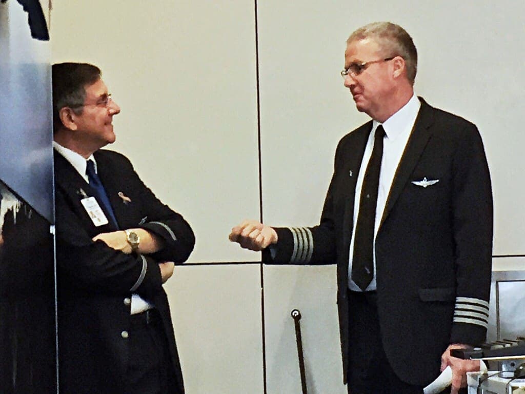 Two elderly pilots talking to each other at an airport