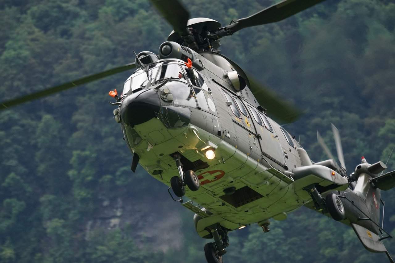 A helicopter with its blades spinning and flying low