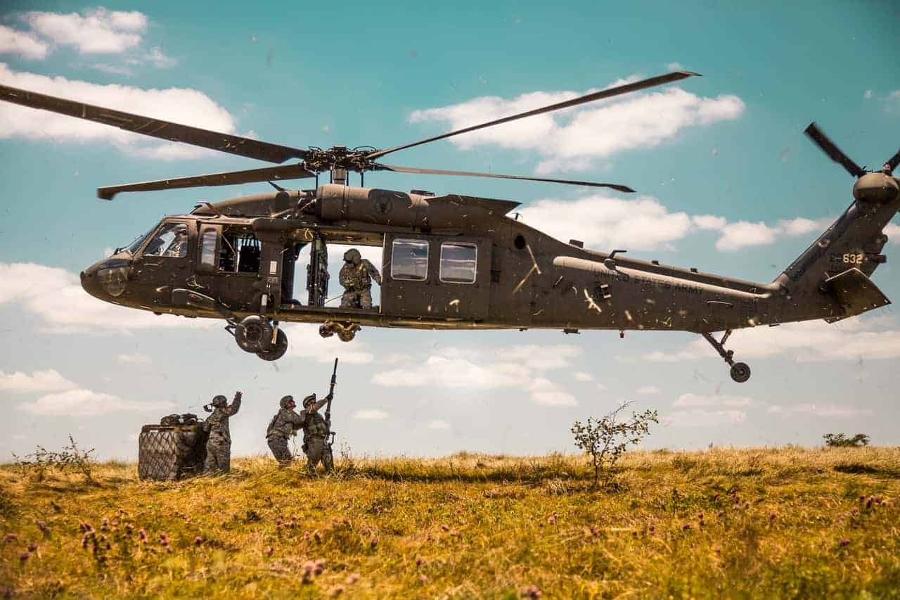 A military helicopter with troops jumping out of it