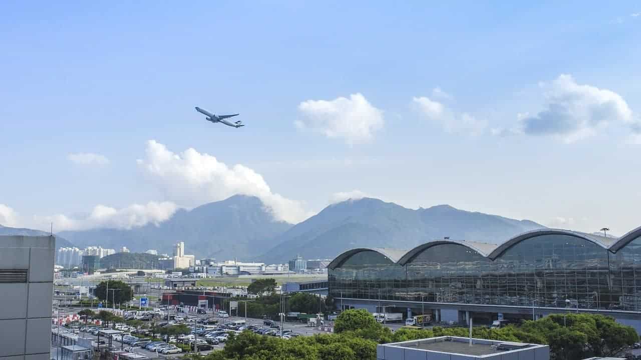 A commercial airliner climbing in altitude over a city