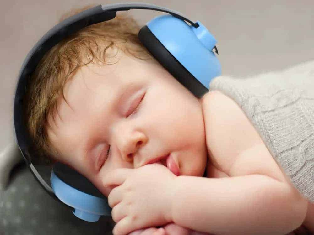 A baby wearing ear muffs as he sleeps