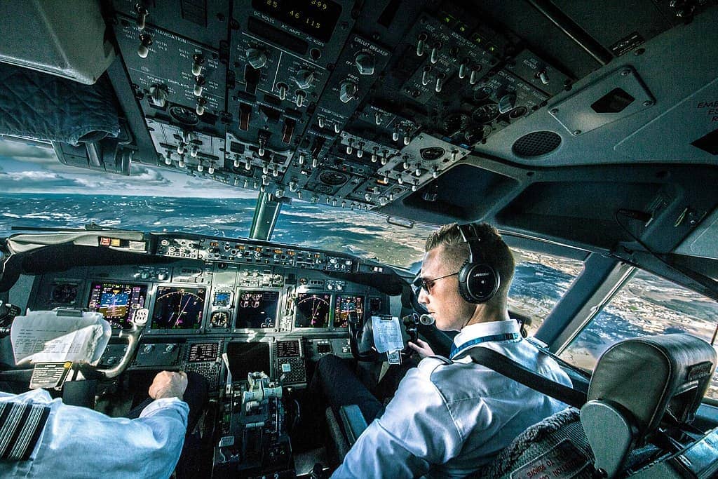 Two pilots sitting in a cockpit and controlling the plane