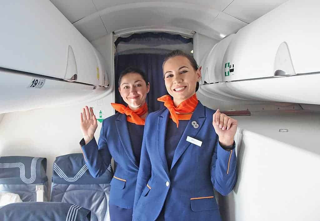 Two tall smiling flight attendants in uniform