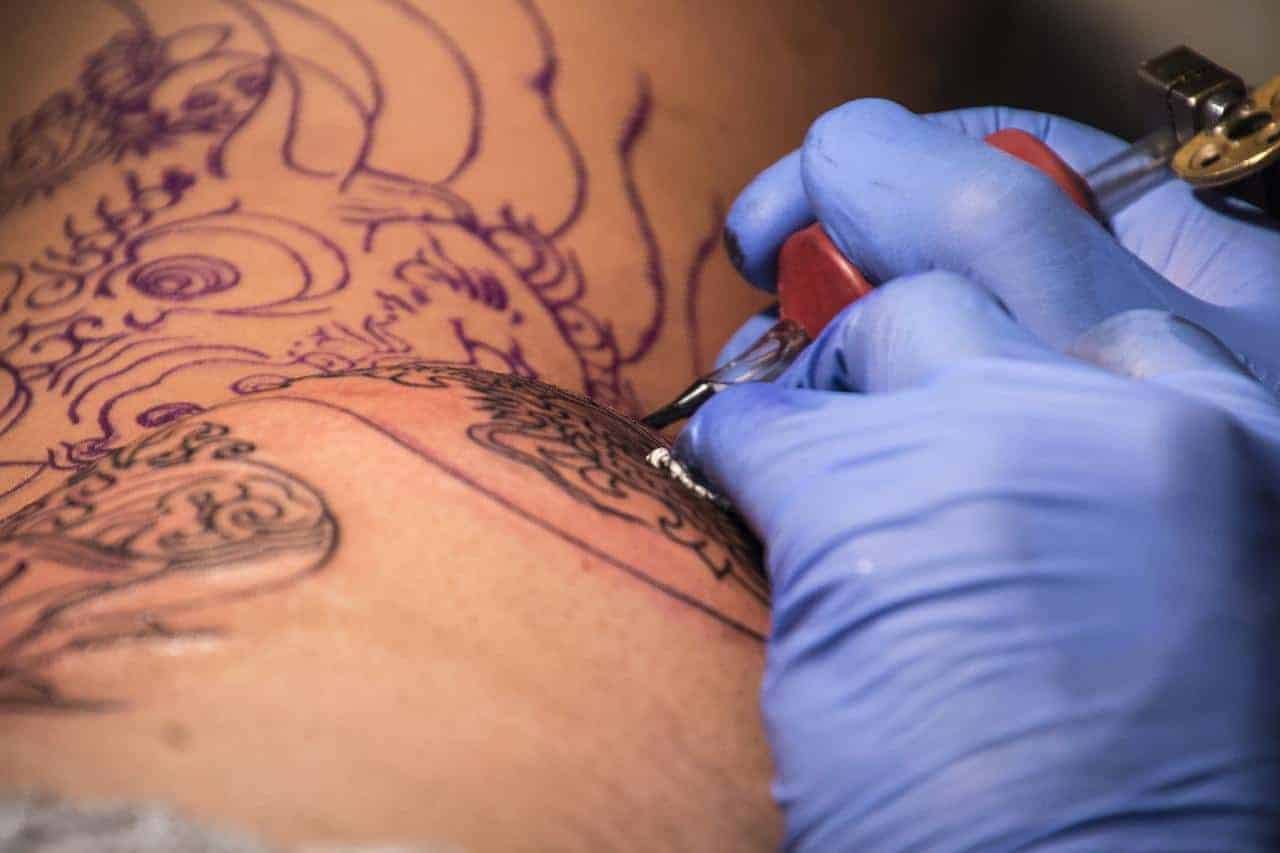 A tattoo artist tatooing a flight attendant