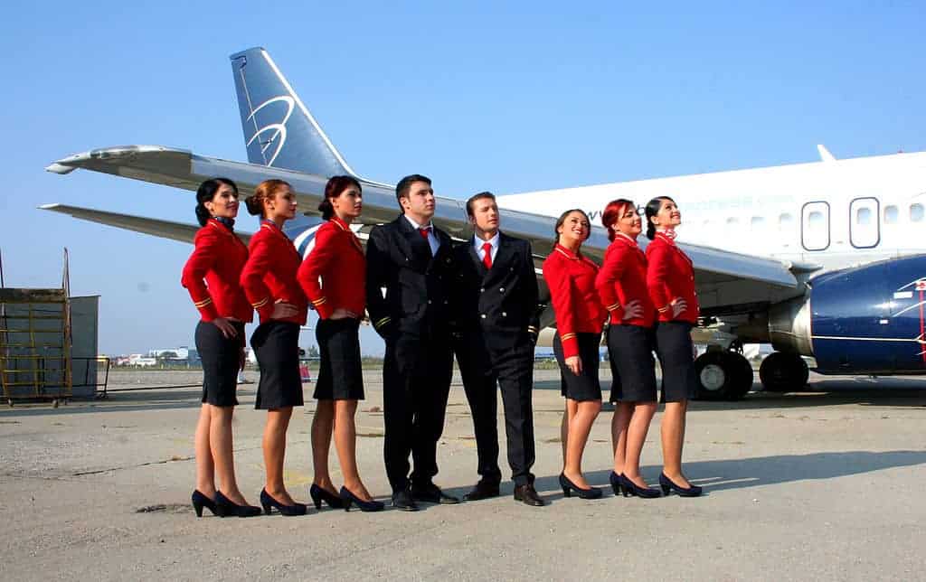 6 flight attendants standing next to two pilots