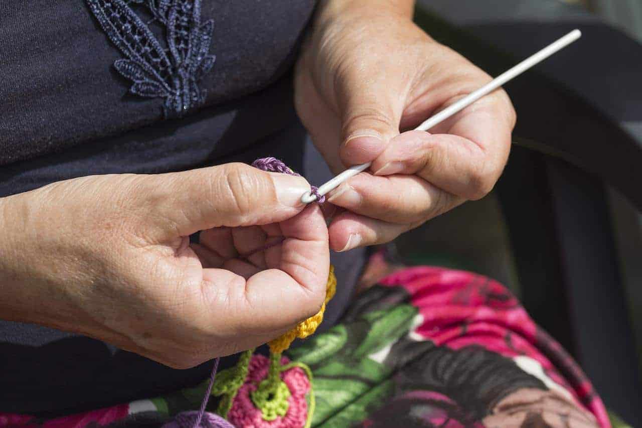 A woman crocheting and using crochet hooks
