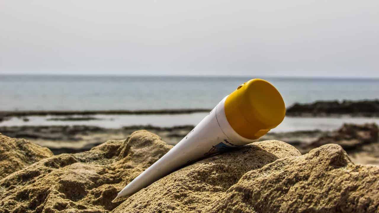 A container of sunscreen in the sand at the beach