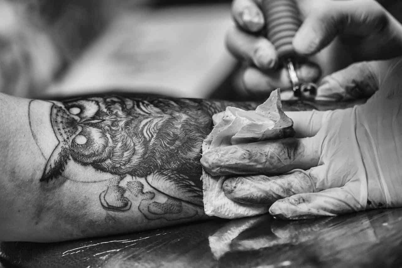A tattoo artist tattooing a man's arm