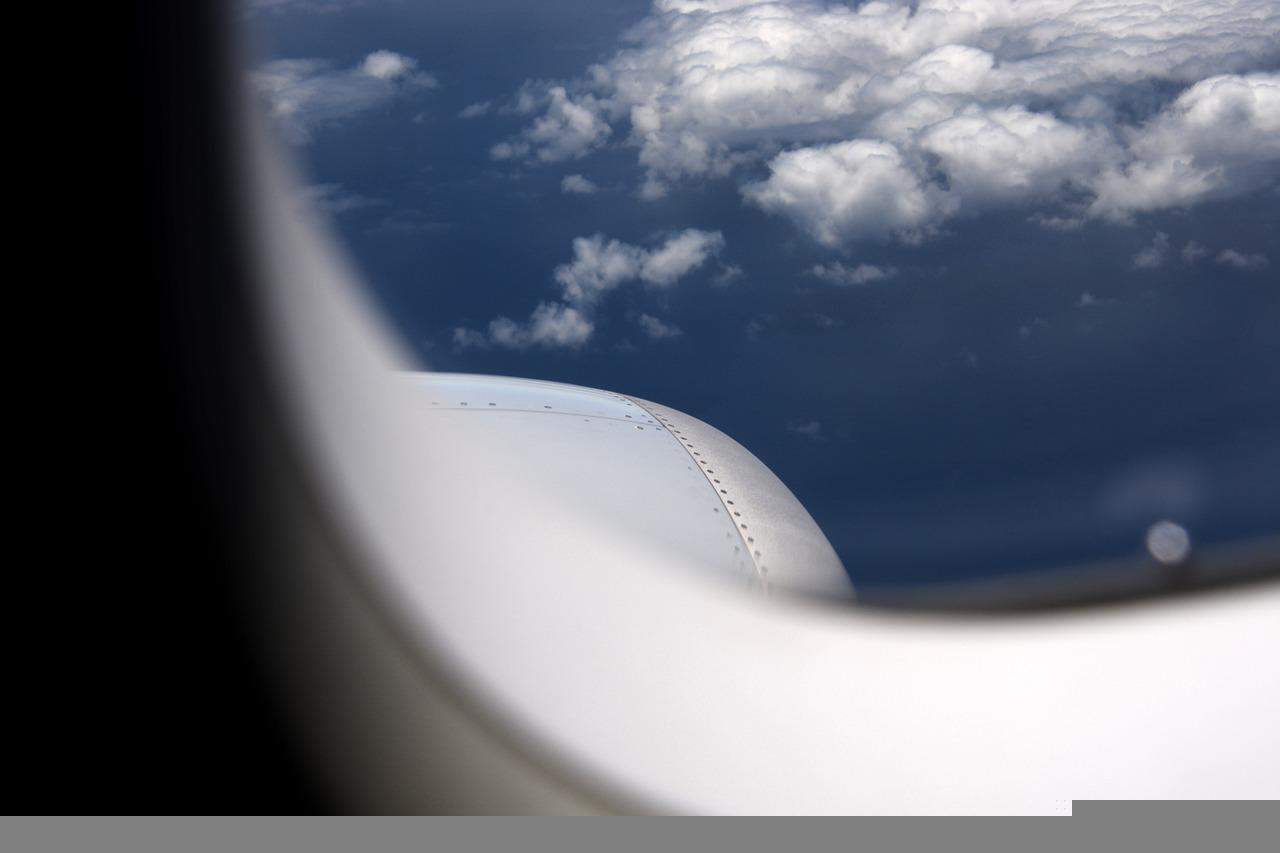 A view from a plane's window showing blue, cloudy skies