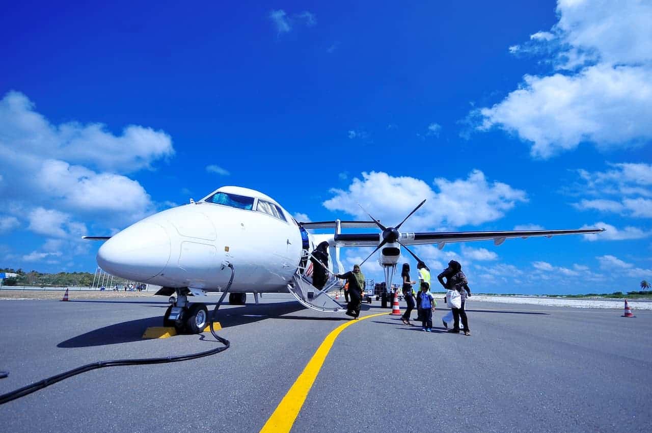 A private plane parked on a runway with customs officials approaching