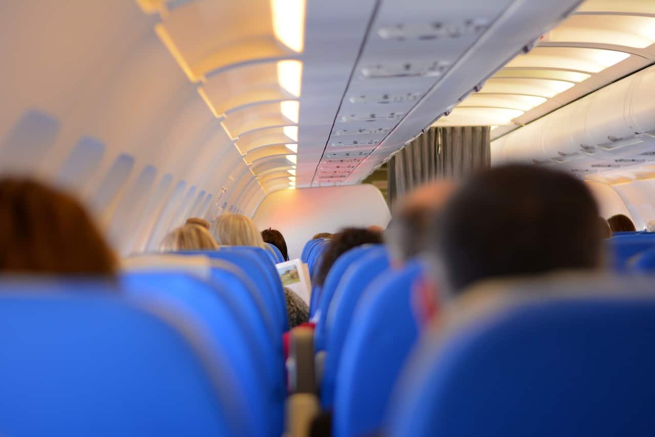 passengers sitting on a plane with blue seats