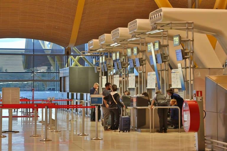 Passengers checking in bags at an empty airport counter