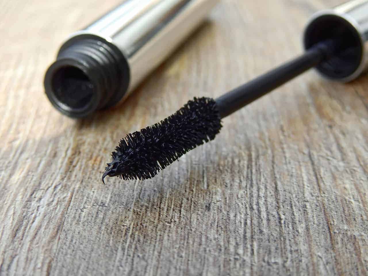 Opened bottle of mascara on a wood table