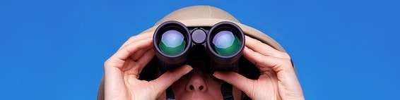 Woman in safari hat looking through binoculars