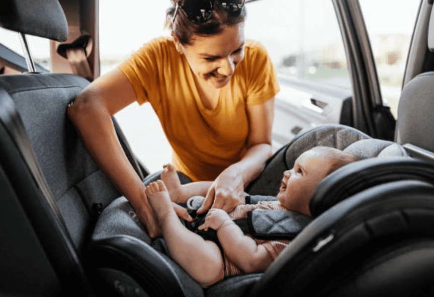 mom adjusting the belt in her child's car seat