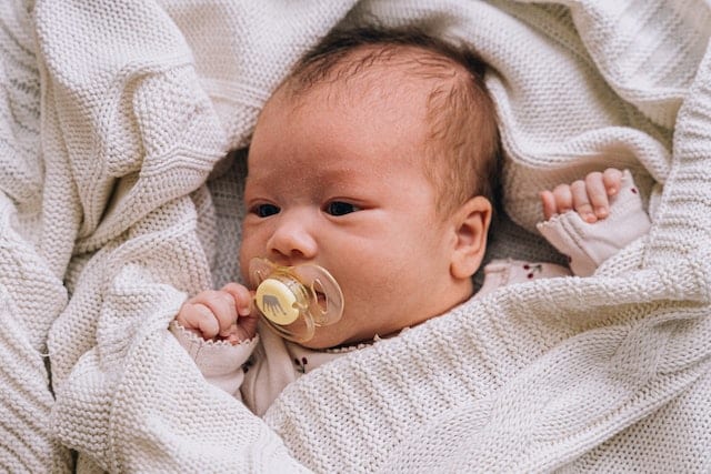 newborn baby with pacifier in mouth